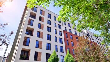 Modern residential building with new apartments in a green residential area. Eco architecture. Green tree and new apartment building. The harmony of nature and modernity. photo