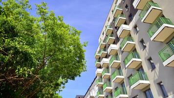 Modern residential building with new apartments in a green residential area. Eco architecture. Green tree and new apartment building. The harmony of nature and modernity. photo