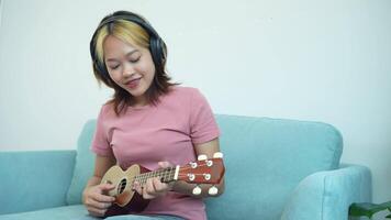 mulher é jogando uma ukulele. ela é vestindo uma Rosa camisa video