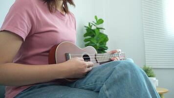 mulher é jogando uma ukulele. ela é vestindo uma Rosa camisa video