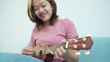 donna è giocando un' ukulele. lei è indossare un' rosa camicia video