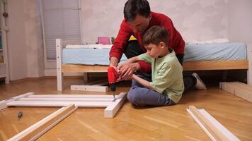 Vater unterrichtet seine Sohn zu spannen Schrauben und Schrauben mit ein elektrisch Schraubendreher video