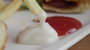 detalle Disparo de francés papas fritas bebiendo mayonesa en mesa video