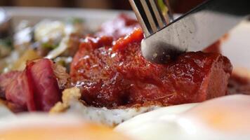 Using fork and knife to cut sausages mixed with tomato sauce video