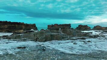 aereo superiore Visualizza di onde rompere su rocce nel un' blu oceano. mare onde su bellissimo spiaggia aereo Visualizza drone. uccelli occhio Visualizza di oceano onde Crashing contro un vuoto pietra roccia scogliera a partire dal sopra video