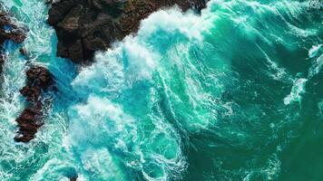 Antenne oben Aussicht von Wellen brechen auf Felsen im ein Blau Ozean. Meer Wellen auf schön Strand Antenne Aussicht Drohne. Vogel Auge Aussicht von Ozean Wellen abstürzen gegen ein leeren Stein Felsen Cliff von über video