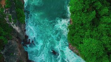 aérien Haut vue de vagues Pause sur rochers dans une bleu océan. mer vagues sur magnifique plage aérien vue drone. des oiseaux œil vue de océan vagues s'écraser contre un vide pierre Roche falaise de au dessus video