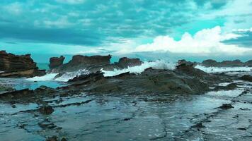 antenn topp se av vågor ha sönder på stenar i en blå hav. hav vågor på skön strand antenn se Drönare. fåglar öga se av hav vågor kraschar mot ett tömma sten sten klippa från ovan video