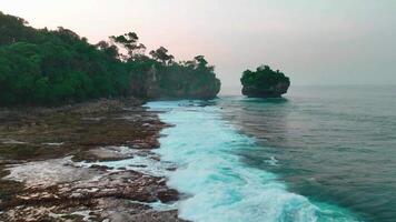 Antenne oben Aussicht von Wellen brechen auf Felsen im ein Blau Ozean. Meer Wellen auf schön Strand Antenne Aussicht Drohne. Vogel Auge Aussicht von Ozean Wellen abstürzen gegen ein leeren Stein Felsen Cliff von über video