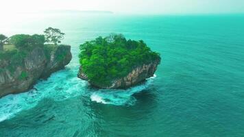 aerial top view of waves break on rocks in a blue ocean. sea waves on beautiful beach aerial view drone. bird's eye view of ocean waves crashing against an empty stone rock cliff from above video