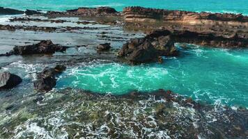 aérien Haut vue de vagues Pause sur rochers dans une bleu océan. mer vagues sur magnifique plage aérien vue drone. des oiseaux œil vue de océan vagues s'écraser contre un vide pierre Roche falaise de au dessus video