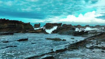 aerial top view of waves break on rocks in a blue ocean. sea waves on beautiful beach aerial view drone. bird's eye view of ocean waves crashing against an empty stone rock cliff from above video