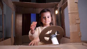 close-up of a girl sitting in a cardboard car and turning the steering wheel video