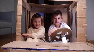 close-up of children play in a cardboard car. Recycling of paper cardboard waste video