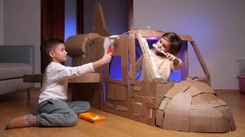 kinderen bouwen een vliegtuig uit van karton. kinderen verf een karton vliegtuig video