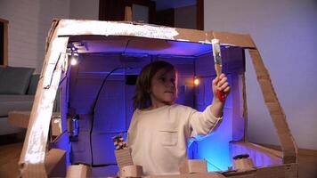 A girl paints the cabin of a cardboard spaceship. video