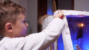 une garçon des peintures le cabine de une papier carton vaisseau spatial avec une brosse. video