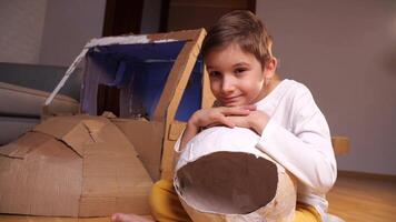 portrait de une garçon avec un astronaute casque suivant à une papier carton jouet vaisseau spatial video