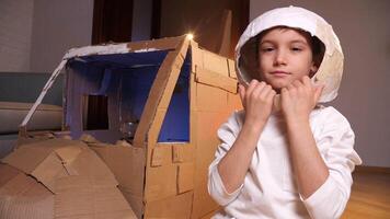 Child plays at home in astronaut, portrait of a cute little boy in space helmet video