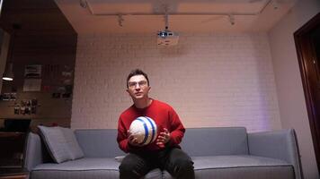 ein Fußball Ventilator im rot Kleider beim Zuhause ist intensiv Aufpassen das Spiel, besorgt video