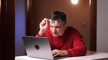de cerca cansado programador, persona de libre dedicación con pobre vista trabajando cerca a ordenador portátil video