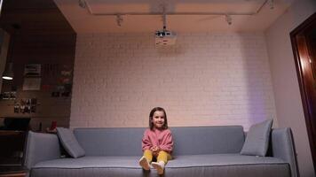 a little girl watches cartoons and films in a home theater on a projector. video