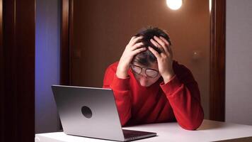 irritato giovane uomo coperture il suo viso con palme nel frustrazione, cattivo notizia su il computer portatile video