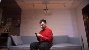 Man typing a message while watching a movie in a home theater video