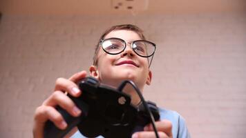 fermer garçon joueur dans des lunettes pièces Jeux sur le console avec une manette de jeu video