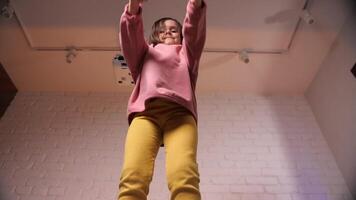 Overjoyed playful little brown haired girl jumping and dancing on sofa video