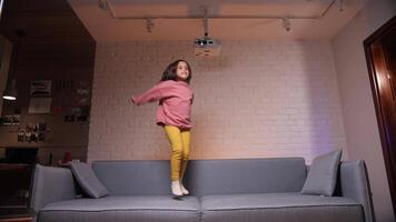 Lycklig liten flicka Hoppar för glädje på de soffa video