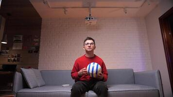 een Mens Bij huis in een rood sweater aan het kijken Amerikaans voetbal, vreugde van scoren een doel video