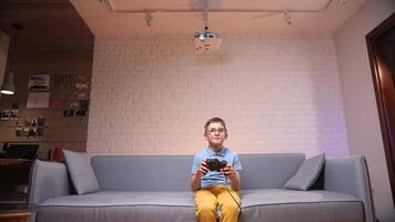 poco ragazzo gamer nerd nel bicchieri giochi Giochi su il consolle con un' gamepad video