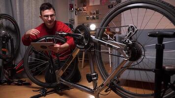 un hombre intentos a arreglar, reparar un bicicleta bicicleta utilizando instrucciones en un tableta video