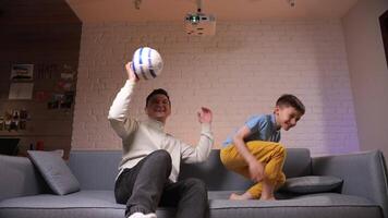 Father and son boy watching a soccer football match on tv television home video