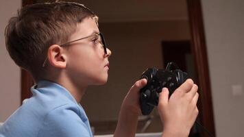 fermer garçon joueur dans des lunettes pièces Jeux sur le console avec une manette de jeu video