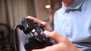 närbild av en svart gamepad, en trösta kontrollant i de händer av en pojke video