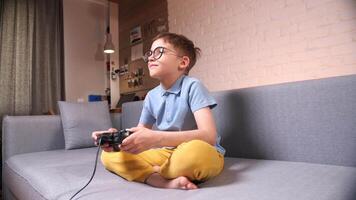 Little boy playing game on gamepad sitting in living room video