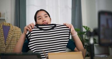 antal fot dolly skott, ung asiatisk kvinna företag ägare försäljning kläder leva strömning på mobil telefon visa ny samling mode kläder till kund ,uppkopplad handla video