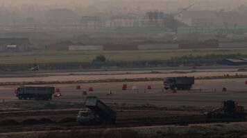 Construction of a new runway at the airport. Construction equipment performing work at sunset. Trucks video