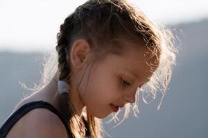 A young girl with braided hair is looking at the camera photo