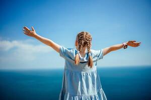 A young girl with pigtails is standing on a beach, looking out at the ocean photo