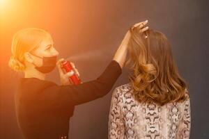 mujer salón peinado. peluquero usos laca para el cabello en clientela pelo en salón, retrato de dos hermosa mujer foto