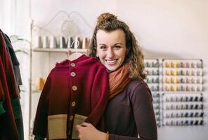 Joyful Woman Holding a Stylish Red Jacket in a Boutique, Store Concept photo