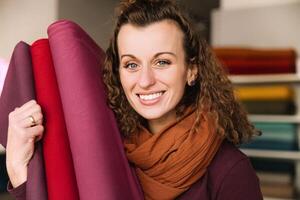 Enthusiastic Woman with Curly Hair Holding Colorful Fabric in a Creative Setting photo