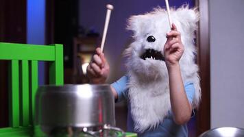 boy child in dog wolf costume for halloween plays drums, a lot of noise at home video