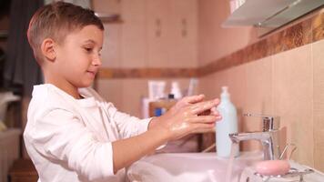 boy soaps his hands with a piece of pink soap in the bathroom video