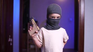 portrait de une petit enfant dans une masque avec une jouet pistolet, enfants Jeu de bandits video
