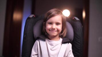 little girl sitting in a child's car seat looking at camera and smiling video