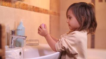 pequeño niña en el baño jabones su manos y lavados su manos a fondo video